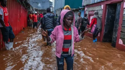 Residents are seen in a flooded street of Mathare neighborhood after heavy rains as they try to evacuate the area with their important belongings in Nairobi, Kenya on April 24, 2024