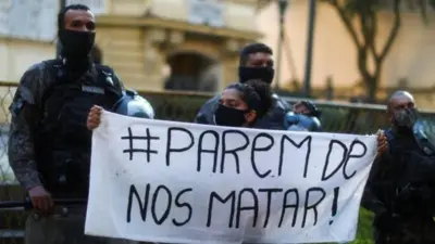 Fotografia colorida mostra mulher jovem negra segurando cartaz "parembetnet casinonos matar"  