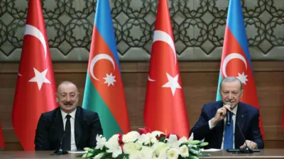 Aliyev ve Erdoğan Azerbaycan ve Türk bayrakları önünde masada oturmuş açıklama yapıyor
