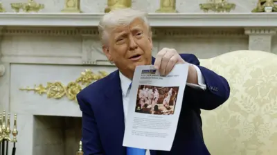 U.S. President Donald Trump holds up a printed article from "American Thinker" while accusing South Africa President Cyril Ramaphosa of state-sanctioned violence against white farmers in South Africa 