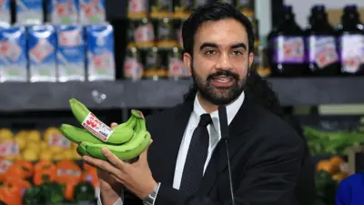 Wali Kota New York City, Zohran Mamdani, memegang beberapa pisang saat berbicara di sebuah pusat distribusi makanan pada 27 Juli 2026, di borough Brooklyn, New York.