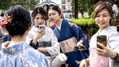 Foreign tourists take selfies in Tokyo's Asakusa district on April 15, 2026. 