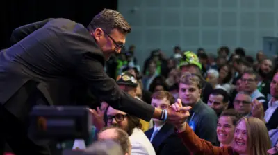 Andy Burnham z brytyjskiej Partii Pracy - były burmistrz Wielkiego Manchesteru i nowo wybrany deputowany do Izby Gmin z okręgu Makerfield - ściska dłoń zwolenniczki po zwycięstwie w wyborach uzupełniających w okręgu Makerfield. Burnham i zwolennicy świętują w lokalu „The Edge Wigan” w Wigan, na północy Anglii. 19 czerwca 2026 r.