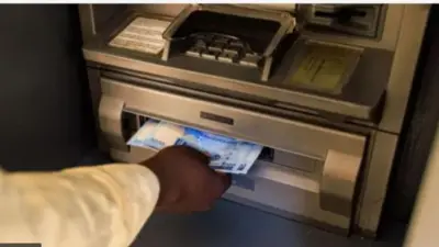 Ọwọ kan n gba owo lati ẹnu ẹrọ to n pọ owo (ATM)