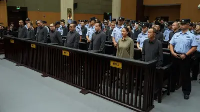 Pessoas em fila em um tribunal, cercadas por agentes de segurança.