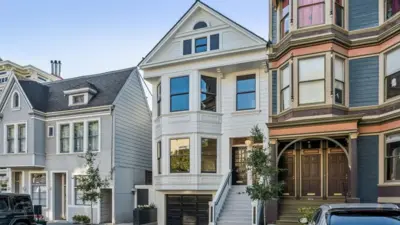 Tres casas en una calle residencial de San Francisco. Las viviendas de tres plantas lucen limpias y bien mantenidas, con plantas y árboles bien cuidados en el exterior.