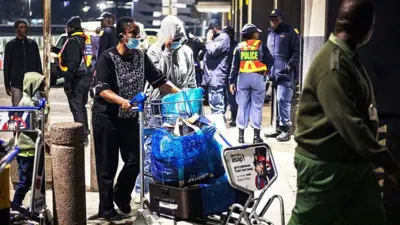 Woman dey push her luggage inside cart for airport