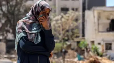 ग़ज़ा के अल शिफ़ा अस्पताल के पास लाशों की तलाश करती महिला