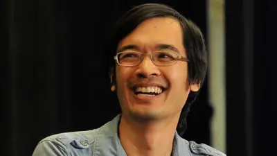 Terence Tao, que usa óculos e veste uma camisa azul, sorri.