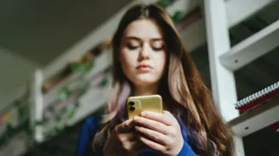 Umukobwa ukiri muto wubitse umutwe uri kureba muri telefone