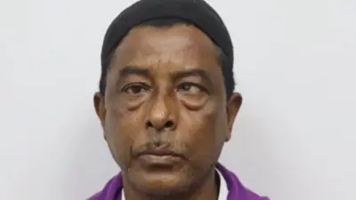 Nurul Amin Shah Alam en la foto con un traje violeta. 