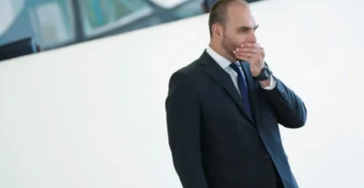 Foto mostra Eduardo Bolsonaro segurando a mão sobre a boca numa expressão que denota certa apreensão
