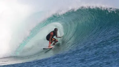 Surfer Matt Grainger rides a wave. He is wearing a black cap on his head.