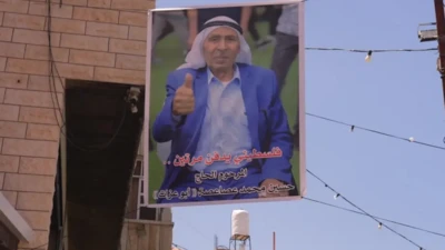 تصویر رنگی یک مرد با کت و شلوار و چفیه که به دیوار نصب شده است