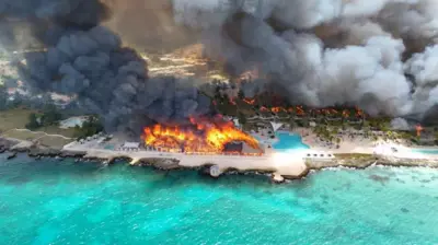 Drone shot of the a large dark cloud of smoke and flames over the Viva Wyndham Dominicus Beach.