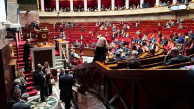 フランス国民議会の議場を、議長席と演壇の横から撮影した写真。半円の階段状の赤い議席に、議員たちがいる
