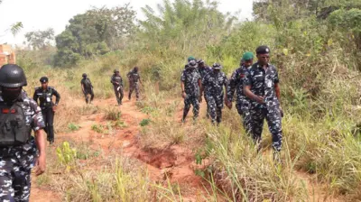 Awọn ọlọpaa n rin kiri ninu igbo kan.