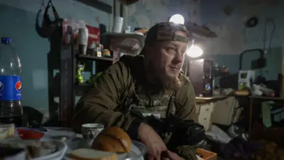 Військовий у спорядженні сидить за обіднім столом в імпровізованій кухні.