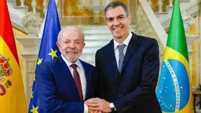 Lula e Sánchez se cumprimentam durante cerimônia oficial de chegada no Palácio de Pedralbes, em Barcelona, na Espanha. Os dois estão diante das bandeiras do Brasil e da Espanha