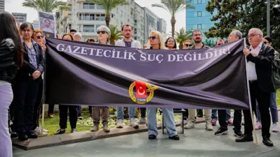 7-8 kişi ellerinde gazetecilik suç değildir yazılı bir pankart tutuyor, pankartta gazeteciler cemiyeti izmir şubesinin logosu var. 