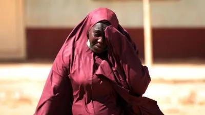 Una mujer cuyo hijo fue secuestrado se lleva la mano a la cabeza en el lugar donde hombres aramado realizaron el plagio de estudiantes en Kankara,  en el estado noroccidental de Katsina, Nigerio, el 15 de diciembre de 2020   