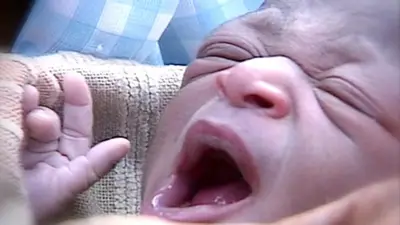 A close-up of a newborn baby yawning.