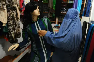 یک زن با چادری در کنار یک مانکن ابریشم پوش