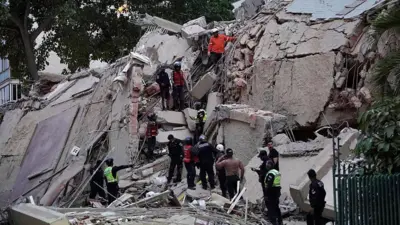 Equipos de rescate buscan víctimas entre los escombros de un edificio colapsado en Caracas tras los terremotos del 24 de junio