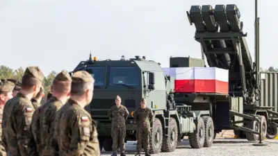 Польські військові стоять біля пускової установки системи протиповітряної оборони Patriot, встановленої на військовій базі. На техніці розміщено польський прапор, а на задньому плані видно елементи ракетного комплексу.
