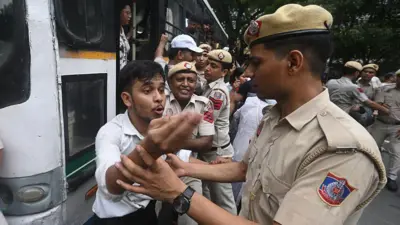 विरोध प्रदर्शन कर रहे स्टूडेंट को हिरासत में लेते हुए दिल्ली पुलिस के जवान
