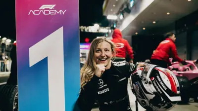 Zwyciężczyni wyścigu Doriane Pin uśmiecha się, świętując po wyścigu. Jest ubrana na czarno, w ręce trzyma kask, a drugą ręką ma zaciśniętą w pięść w geście zwycięstwa.