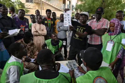 Des scrutateurs tiennent des bulletins de vote pendant le dépouillement de l'élection présidentielle tchadienne dans un bureau de vote à N'Djamena le 6 mai 2024.