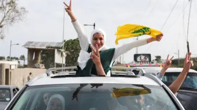 Orang-orang menunjukkan tanda kemenangan dari sebuah kendaraan ketika warga yang mengungsi kembali ke rumah mereka saat melintasi jembatan yang menghubungkan Lebanon selatan dengan bagian lain negara itu, yang sebelumnya terkena serangan Israel, setelah gencatan senjata 10 hari antara Lebanon dan Israel mulai berlaku, di Qasmiyeh, Lebanon, 17 April 2026.