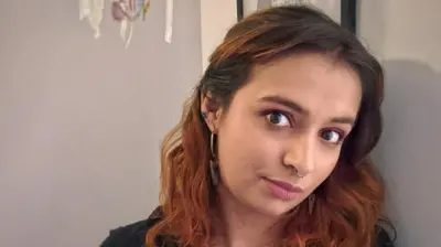 Catalina mira a la cámara con su cabeza inclinada hacia la derecha mientras mantiene una expresión seria en su rostro.