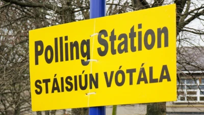 A yellow polling station sign, in English and Irish, on a blue pole