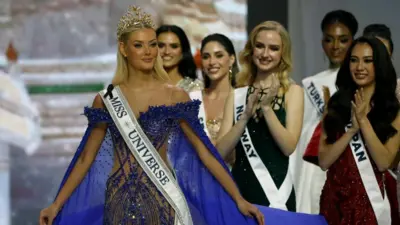 Miss Universe adayları bir sahnede, yürümekte olan geçen yılın Miss Universe'ini alkışlarken