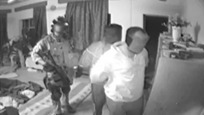 Image from a 2006 SAS squadron compilation video from Iraq showing a member of the squadron with two other men, who appear to be handcuffed