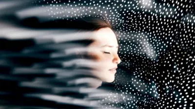 beyaz puantiyeli siyah bir arka planın önünde aydınlık bir kadın yüzü. kadın gözlerini kapatmış