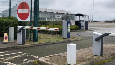 A car park barrier at the entrance to Doncaster Sheffield Airport. The terminal building stands in the distance. 