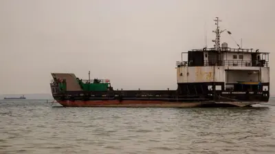 曇り空の下、さびついた船舶が海に浮かんでいる