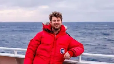 Jake Rosmarin lleva una chaqueta acolchada roja en un barco.