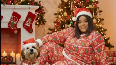 Oloogbe Allwell Ademola ninu aṣọ ọdun Keresimesi. Aja kan wa lẹgbẹẹ rẹ, oṣere naa si kọ ẹyin si igi Keresimesi to n tan ina alaranbara.Abẹala, ibọsẹ tun wa ninu aworan naa pẹlu