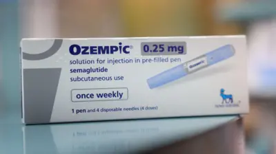 A imagem mostra uma caixa do medicamento Ozempic 0,25 mg, com destaque para a informação de que se trata de uma solução injetável de semaglutida em caneta pré-preenchida, indicada para uso subcutâneo uma vez por semana; a embalagem, predominantemente branca com detalhes em azul, exibe a ilustração da caneta aplicadora, a indicação de que contém uma caneta e quatro agulhas descartáveis (quatro doses) e o logotipo da fabricante Novo Nordisk no canto inferior direito, apoiada sobre uma superfície lisa com o fundo desfocado.