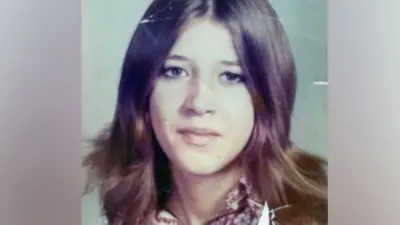 Laura Aimee, en una fotografía escolar de la década de 1970. Tiene el cabello largo y castaño, partido por la mitad, ojos marrones y lleva puesta una blusa estampada.