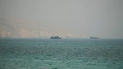 Two vessels are seen in the Strait of Hormuz, surrounded by rocky mountains, from Musandam, Oman