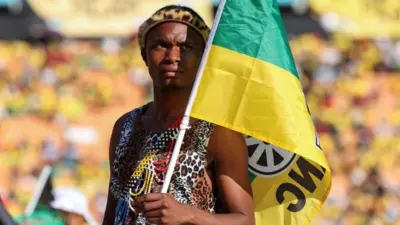 A supporter holds the flag of the African National Congress (ANC) as South African president Cyril Ramaphosa (not pictured) speaks during the party's final rally ahead of the upcoming elections at the FNB Stadium in Johannesburg, South Africa May 25, 2024