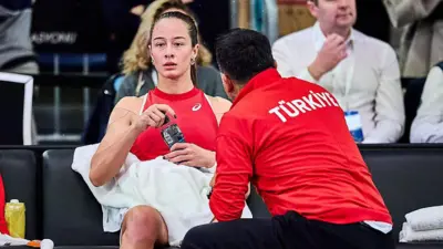 Zeynep Sönmez elinde su ileri bakıyor. Yanında Türkiye forması giyen hocası eğilmiş durumda bir şeyler anlatıyor