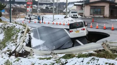 یک جاده که در اثر زلزله گودالی در آن ایجاد شده و خودرویی در حال سقوط در آن است