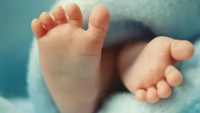 Imagem fechada dos pés de um bebê envolto em cobertor azul