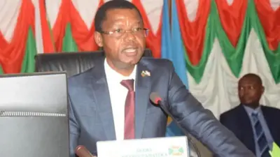 Emmanuel Sinzohagera yambaye ikositimu na karuvati arimo kuvuga ijambo muri 'micro'. 